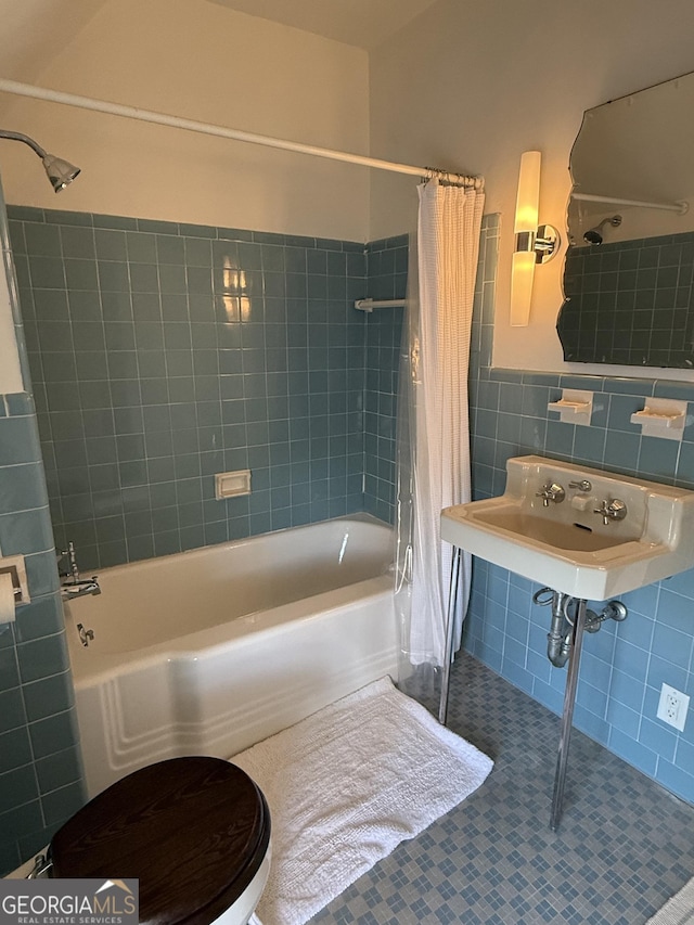 full bath with tile patterned floors, a sink, tile walls, wainscoting, and shower / bathtub combination with curtain