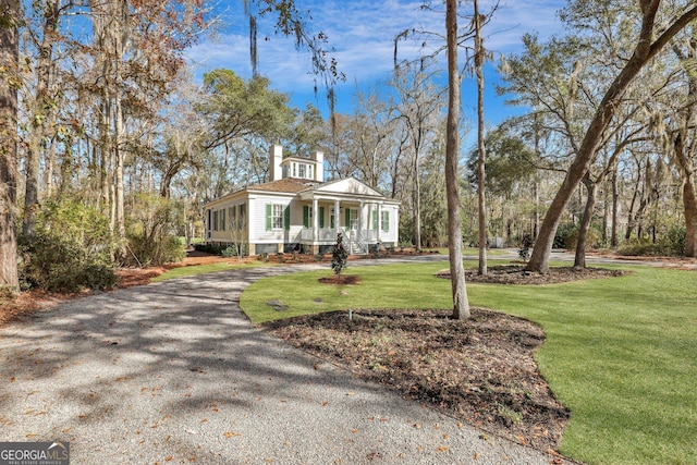 192 Myrtle Grove Ln, Richmond Hill, GA 31324 - view of front of property with covered porch, aphalt driveway, a chimney, and a front lawn