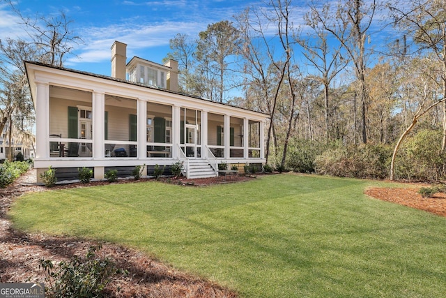 192 Myrtle Grove Ln, Richmond Hill, GA 31324 - back of property with a sunroom, a lawn, and a chimney