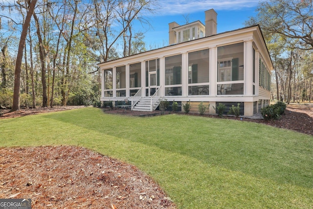 192 Myrtle Grove Ln, Richmond Hill, GA 31324 - back of house with a chimney, a yard, and a sunroom