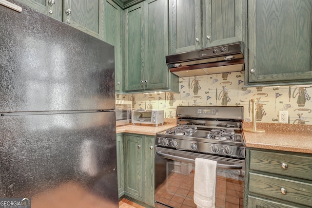 192 Myrtle Grove Ln, Richmond Hill, GA 31324 - kitchen featuring green cabinets, under cabinet range hood, freestanding refrigerator, and stainless steel gas stove