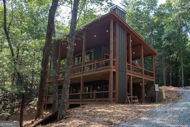 rear view of property with a view of trees and a chimney