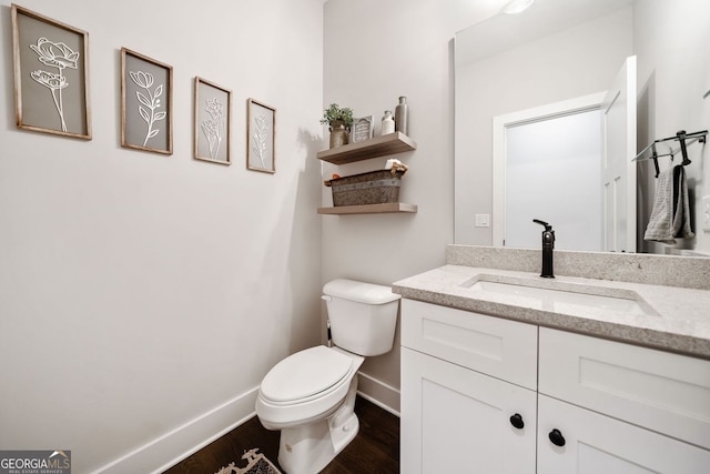 bathroom with wood finished floors, baseboards, vanity, and toilet