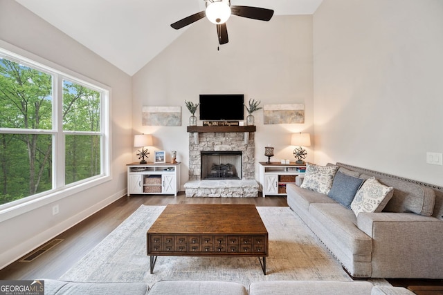 living area with wood finished floors, visible vents, a fireplace, high vaulted ceiling, and ceiling fan