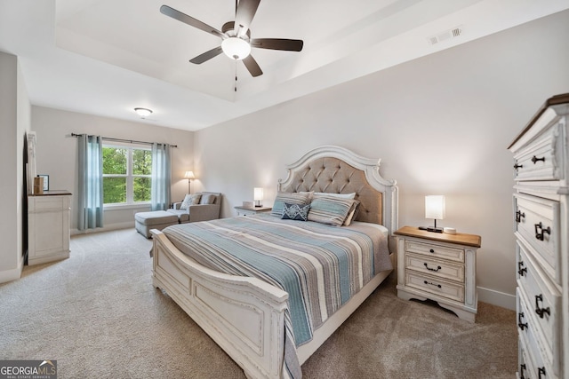 bedroom featuring a tray ceiling, baseboards, visible vents, light colored carpet, and a ceiling fan