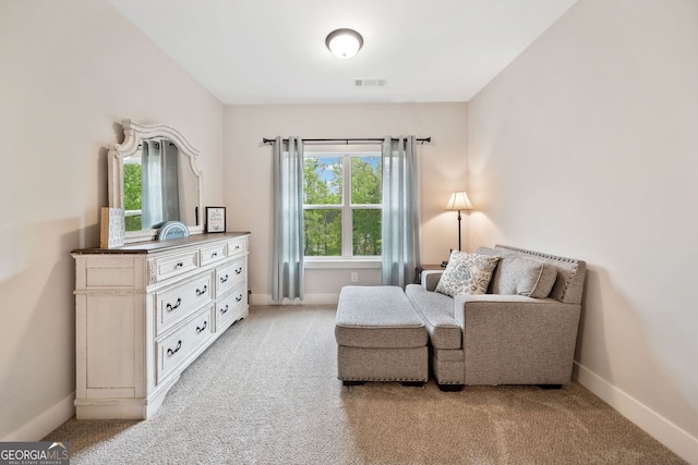 living area featuring visible vents, baseboards, and light carpet