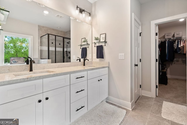 full bath with a sink, double vanity, baseboards, a spacious closet, and a shower stall