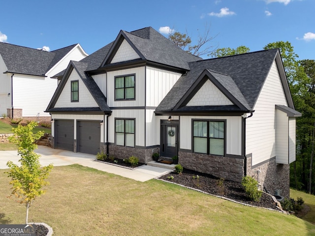 view of front of home with driveway, stone siding, roof with shingles, a front yard, and a garage