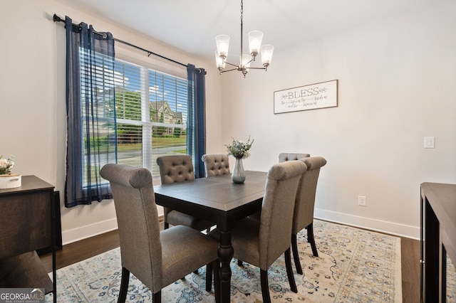 dining room featuring wood finished floors, baseboards, and a notable chandelier