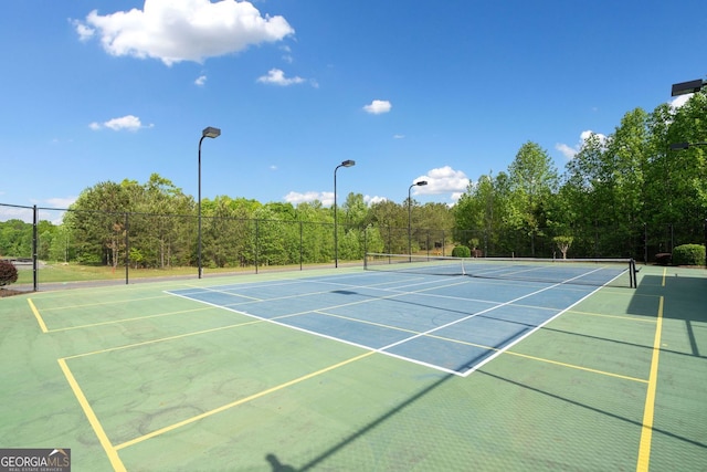 view of tennis court with community basketball court and fence