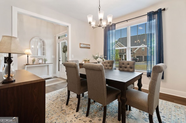 dining space with a wealth of natural light, baseboards, wood finished floors, and an inviting chandelier