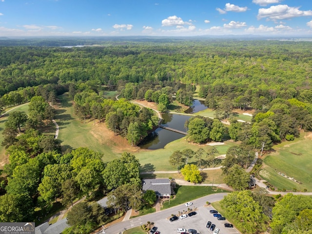 aerial view featuring golf course view, a wooded view, and a water view