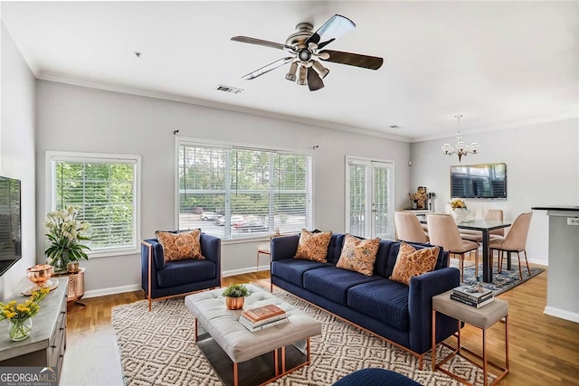 unfurnished living room with baseboards, crown molding, light wood-type flooring, and ceiling fan with notable chandelier