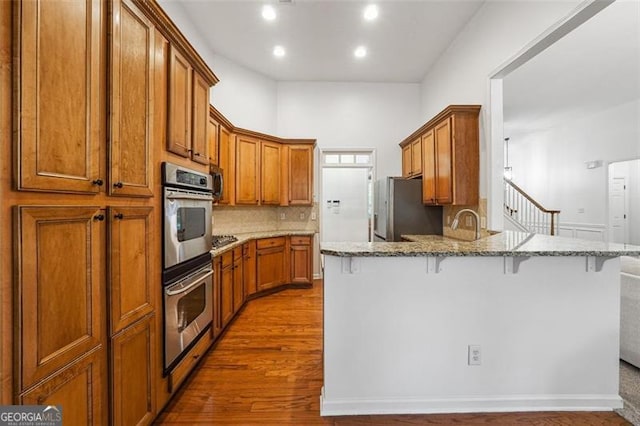 7045 Mountain Xing, Cumming, GA 30041 - kitchen with a peninsula, appliances with stainless steel finishes, a kitchen breakfast bar, and brown cabinets