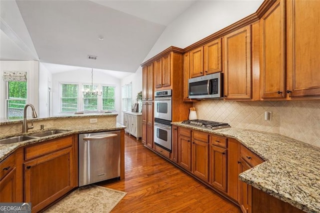 7045 Mountain Xing, Cumming, GA 30041 - kitchen featuring lofted ceiling, stainless steel appliances, a sink, and brown cabinets