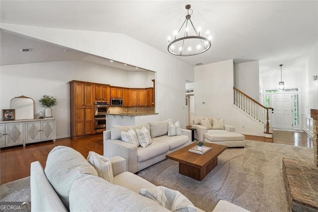 7045 Mountain Xing, Cumming, GA 30041 - living room featuring stairway, vaulted ceiling, a chandelier, dark wood finished floors, and visible vents