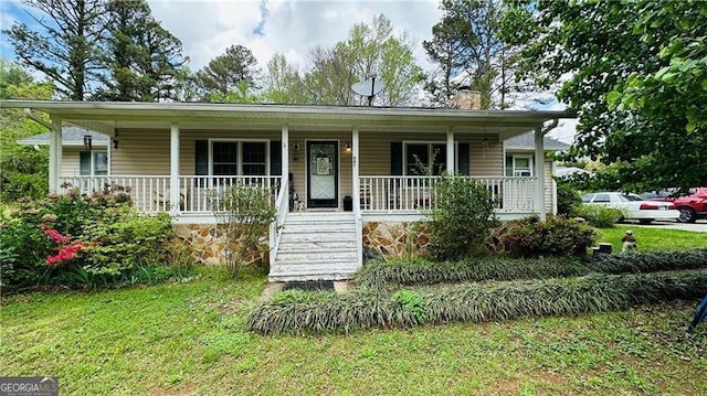 view of front facade featuring a front yard, a chimney, and covered porch