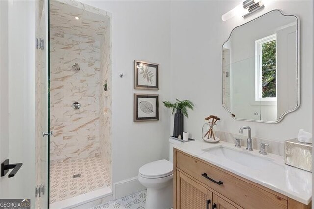 full bath with a tile shower, toilet, and vanity