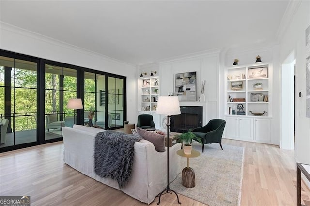 living room with a high end fireplace, wood finished floors, crown molding, and built in features
