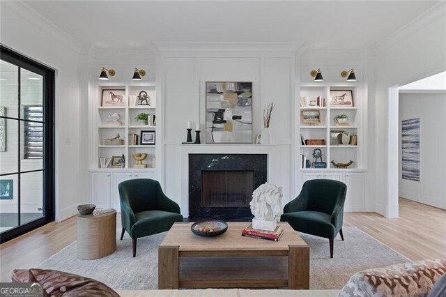 living area with a premium fireplace, light wood-type flooring, built in features, and ornamental molding