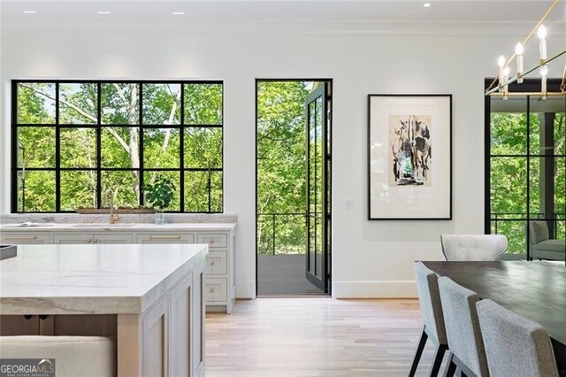 doorway with light wood-style floors, a healthy amount of sunlight, baseboards, and a sink