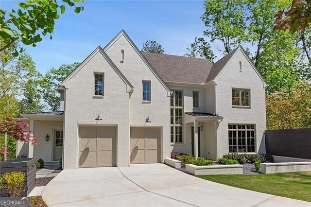 view of front of house featuring brick siding, concrete driveway, an attached garage, metal roof, and a standing seam roof
