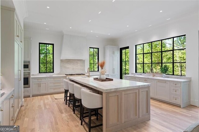 kitchen with light stone counters, light wood-style floors, a spacious island, and stainless steel appliances