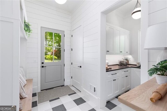 doorway to outside featuring light floors, ornamental molding, and visible vents