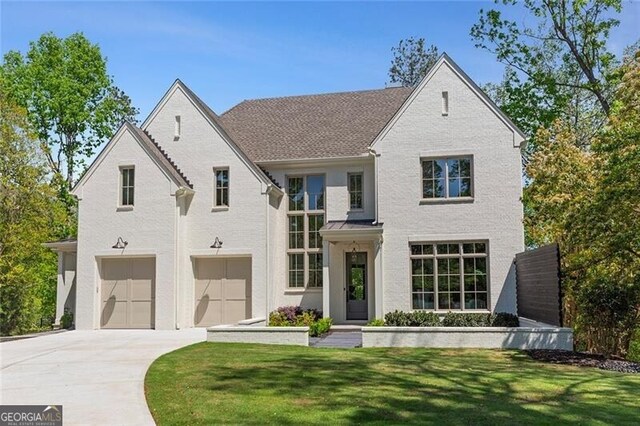 view of front of home featuring brick siding, an attached garage, a front yard, and concrete driveway