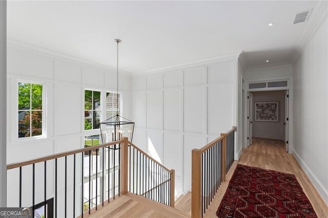 corridor with light wood finished floors, visible vents, recessed lighting, an upstairs landing, and ornamental molding