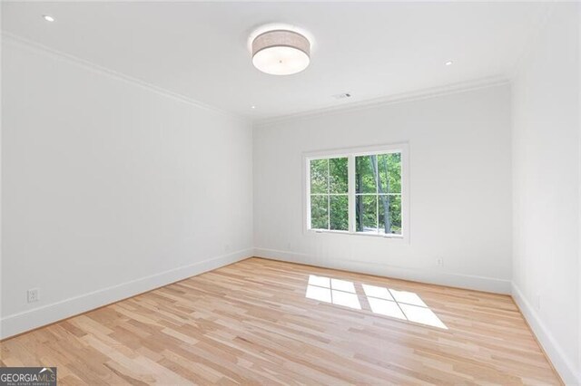 empty room with baseboards, wood finished floors, and ornamental molding