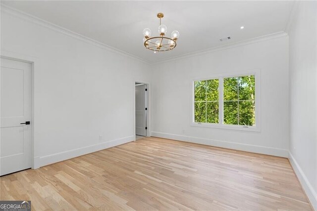 unfurnished room with light wood finished floors, baseboards, a notable chandelier, and crown molding