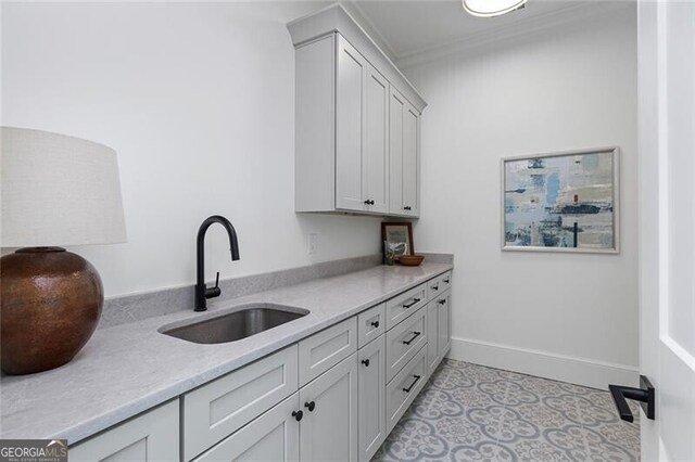 washroom featuring light tile patterned flooring, crown molding, baseboards, and a sink