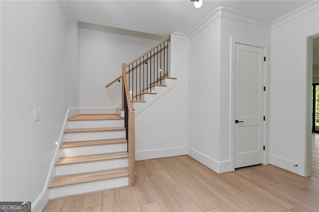 stairway with baseboards, crown molding, and wood finished floors