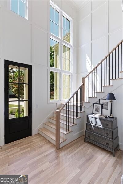 entrance foyer featuring baseboards, wood finished floors, a towering ceiling, and stairway