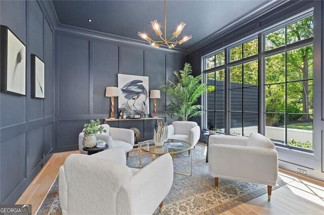 living area with a chandelier, wood finished floors, and a decorative wall