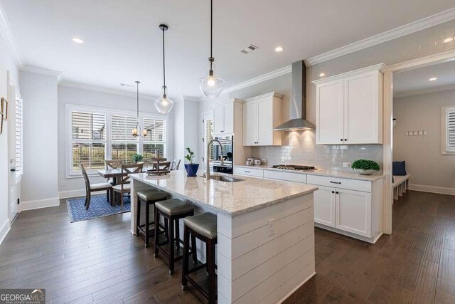 4405 Croftshire Pl, Cumming, GA 30040 - kitchen with wall chimney exhaust hood, appliances with stainless steel finishes, a sink, baseboards, and a breakfast bar area
