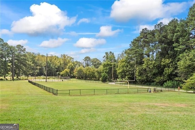 view of community featuring a rural view, a yard, and fence
