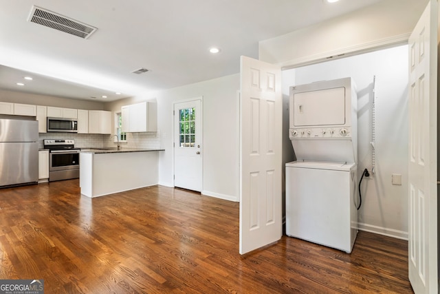 1541 Pontiac Pl SE, Atlanta, GA 30315 - kitchen with dark wood-style floors, visible vents, white cabinetry, stacked washing maching and dryer, and appliances with stainless steel finishes