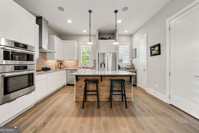 986 Mauldin St SE, Atlanta, GA 30316 - kitchen with backsplash, appliances with stainless steel finishes, a sink, a breakfast bar, and wall chimney exhaust hood