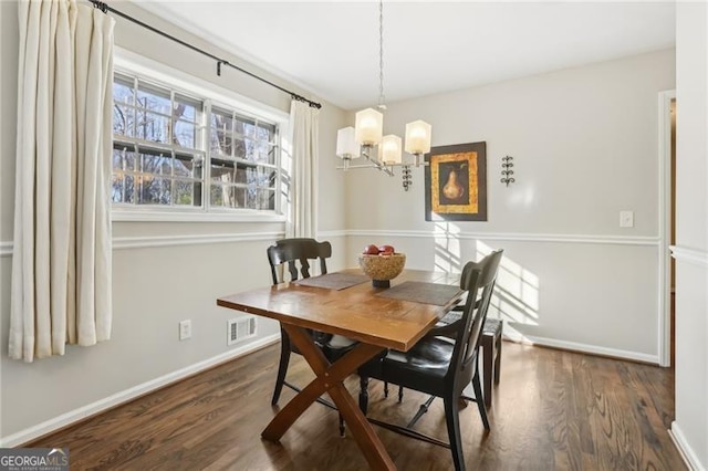 dining space featuring baseboards, an inviting chandelier, and dark wood-style flooring