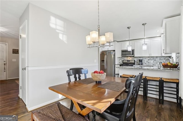 dining space featuring baseboards, a chandelier, and dark wood-type flooring