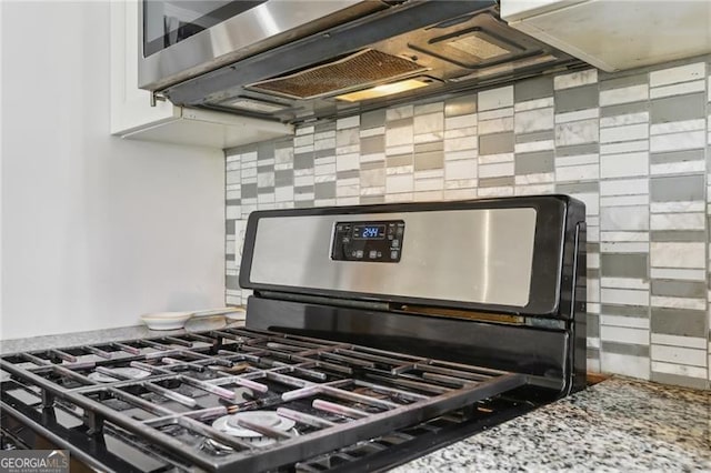 room details featuring stone countertops, exhaust hood, gas range, and tasteful backsplash