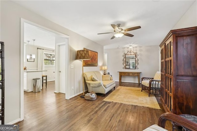 sitting room with baseboards, a ceiling fan, and wood finished floors