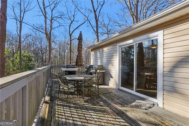 deck with outdoor dining space and a grill
