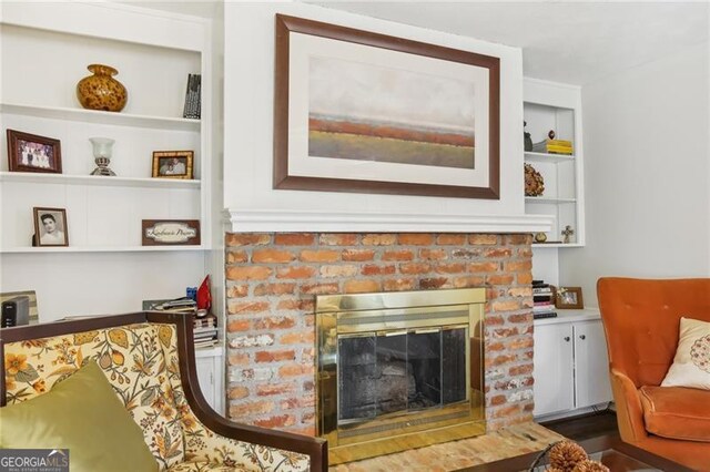 living area featuring a brick fireplace and built in shelves