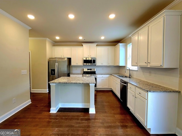 kitchen featuring a center island, a sink, stainless steel appliances, white cabinets, and ornamental molding