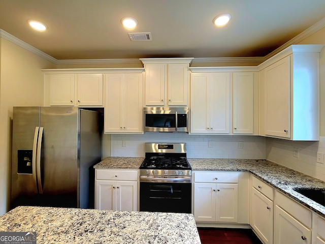 kitchen featuring white cabinets, stainless steel appliances, visible vents, and crown molding