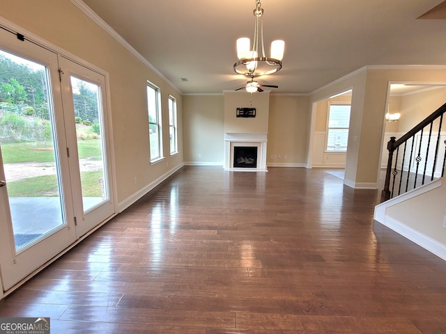 unfurnished living room featuring dark wood finished floors, stairs, a fireplace with raised hearth, and ceiling fan with notable chandelier