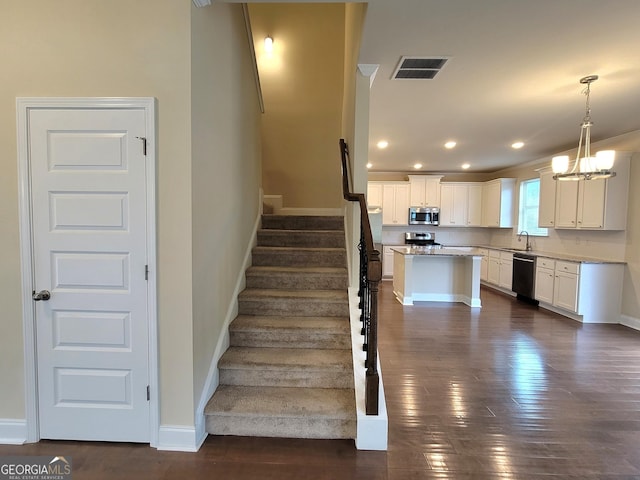 stairs featuring recessed lighting, wood finished floors, visible vents, baseboards, and a notable chandelier